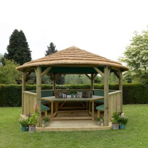 Forest Garden 4.7m Hexagonal Wooden Garden Gazebo with Thatched Roof - Furnished with Table, Benches and Cushions (Green)